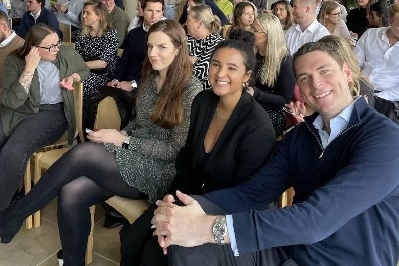 3 people sat smiling at camera